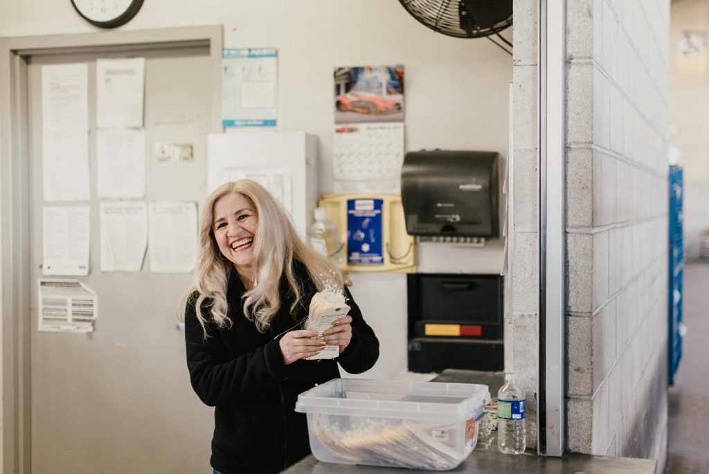 A smiling lady with label tags in her hand at goodwill donation center