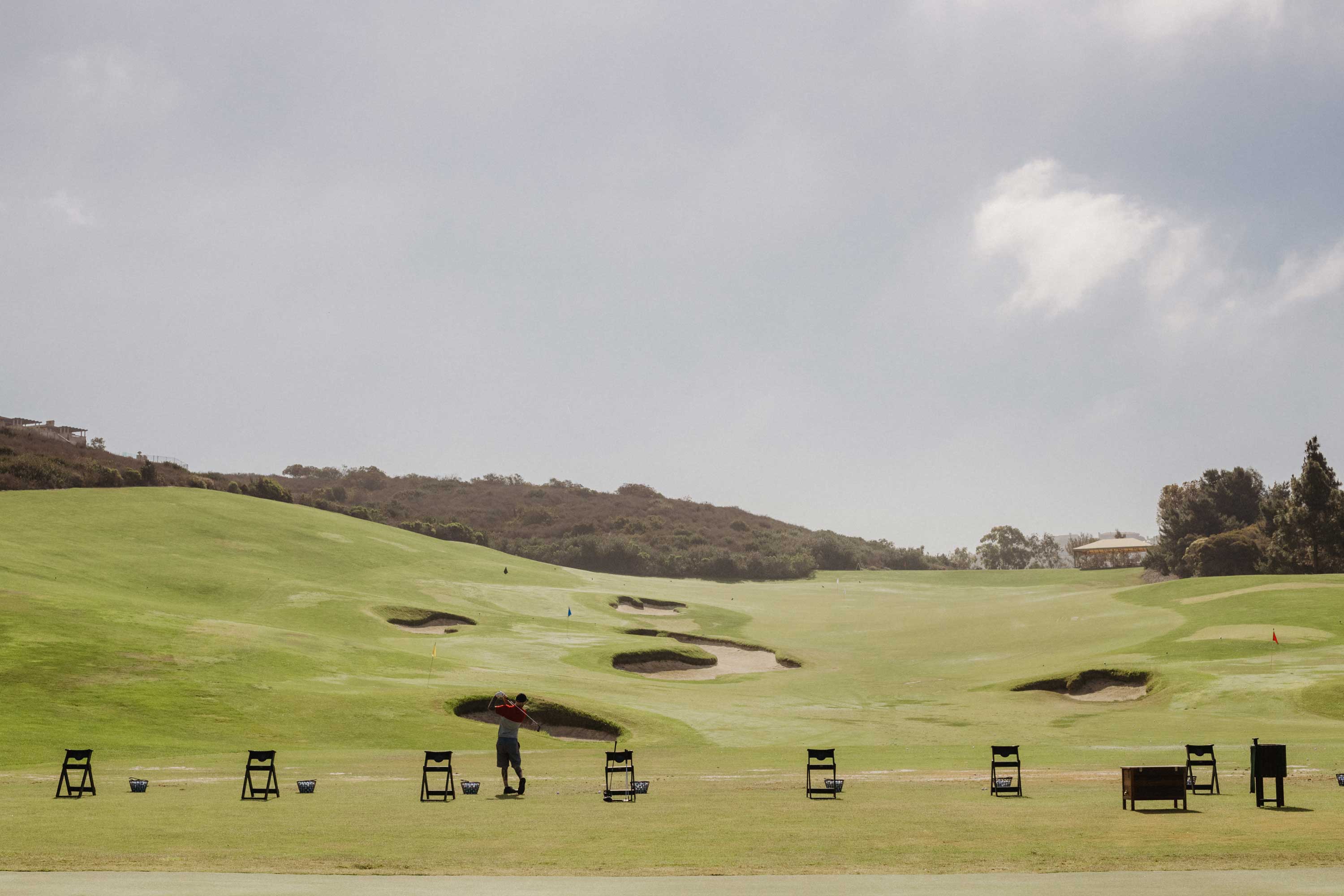 Man hitting golf balls at Pelican Hill golf course driving range.