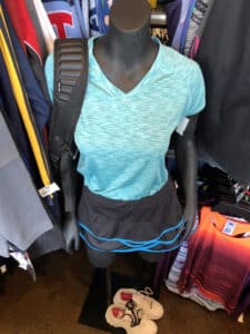 Mannequin with cyan top, grey shorts, and backpack displayed inside Goodwill Store & Donation Center