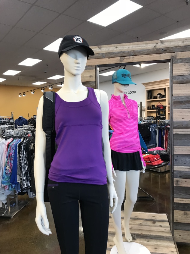 Mannequin with purple vest, black pants, cap, and backpack displayed inside Goodwill Store & Donation Center