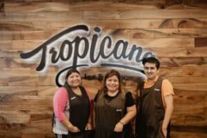 Three Goodwill of Orange County employees standing in front of Tropicana sign