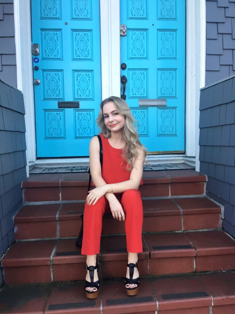 Woman sitting on steps wearing a red jumpsuit