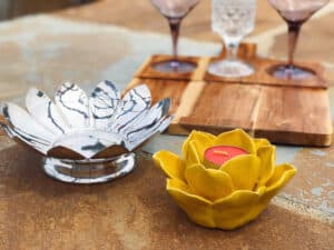 Yellow and chrome flower decor with three mini glass cups on a wooden board