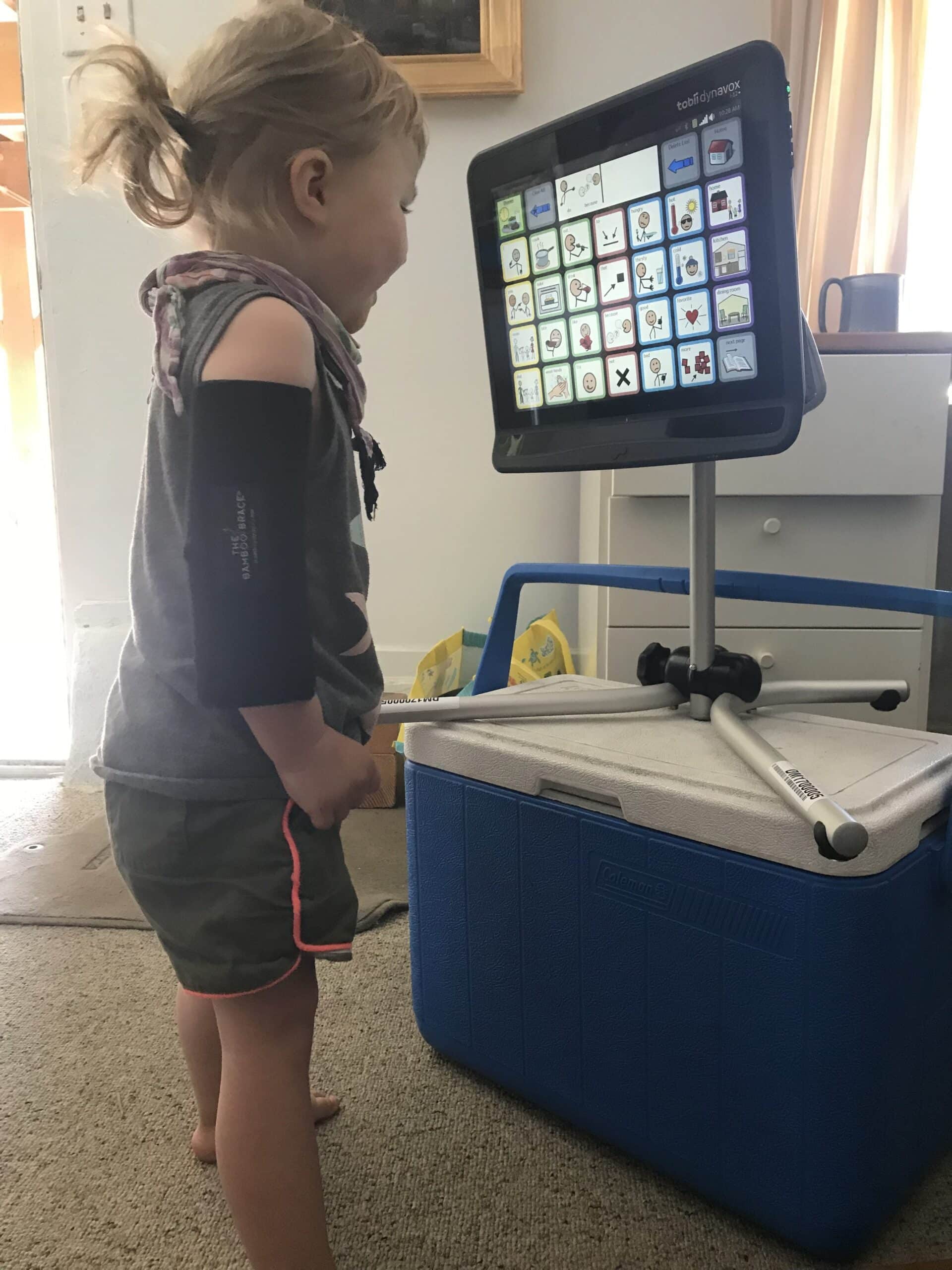 A little girl with neurological disorder looking at an eye-gaze speech generating device by TobiiDynavox, in which she uses her eyes to communicate.