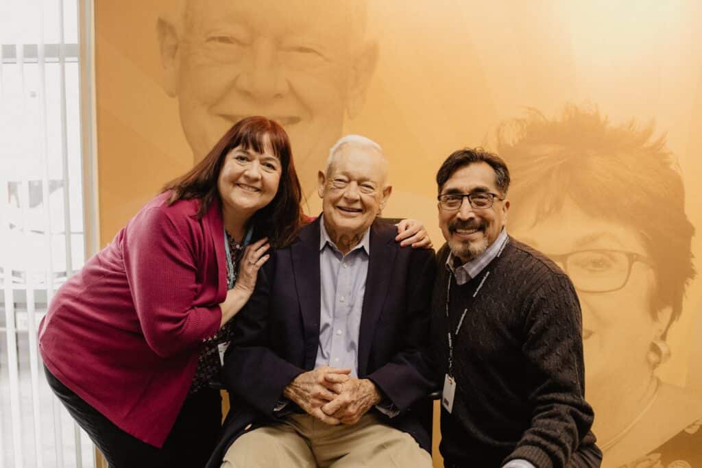 Dan smiling and posing with two other people