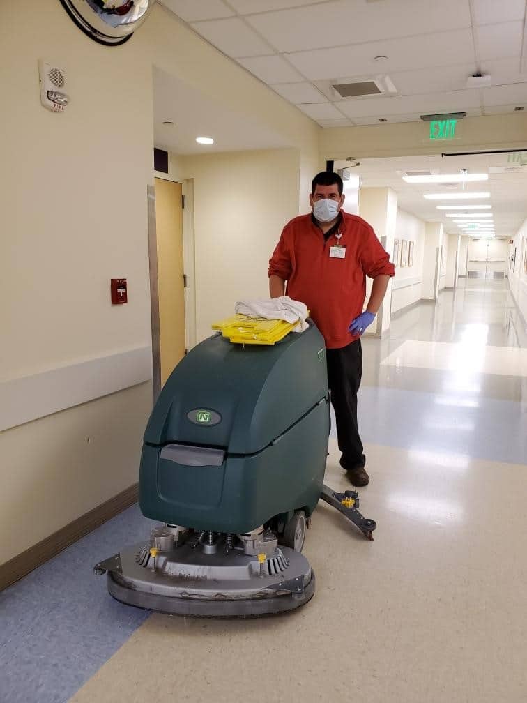 Team member Carlo wearing a mask with cleaning equipments at a hospital corridor