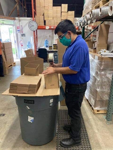 A male worker wearing a mask assembling cardboard boxes