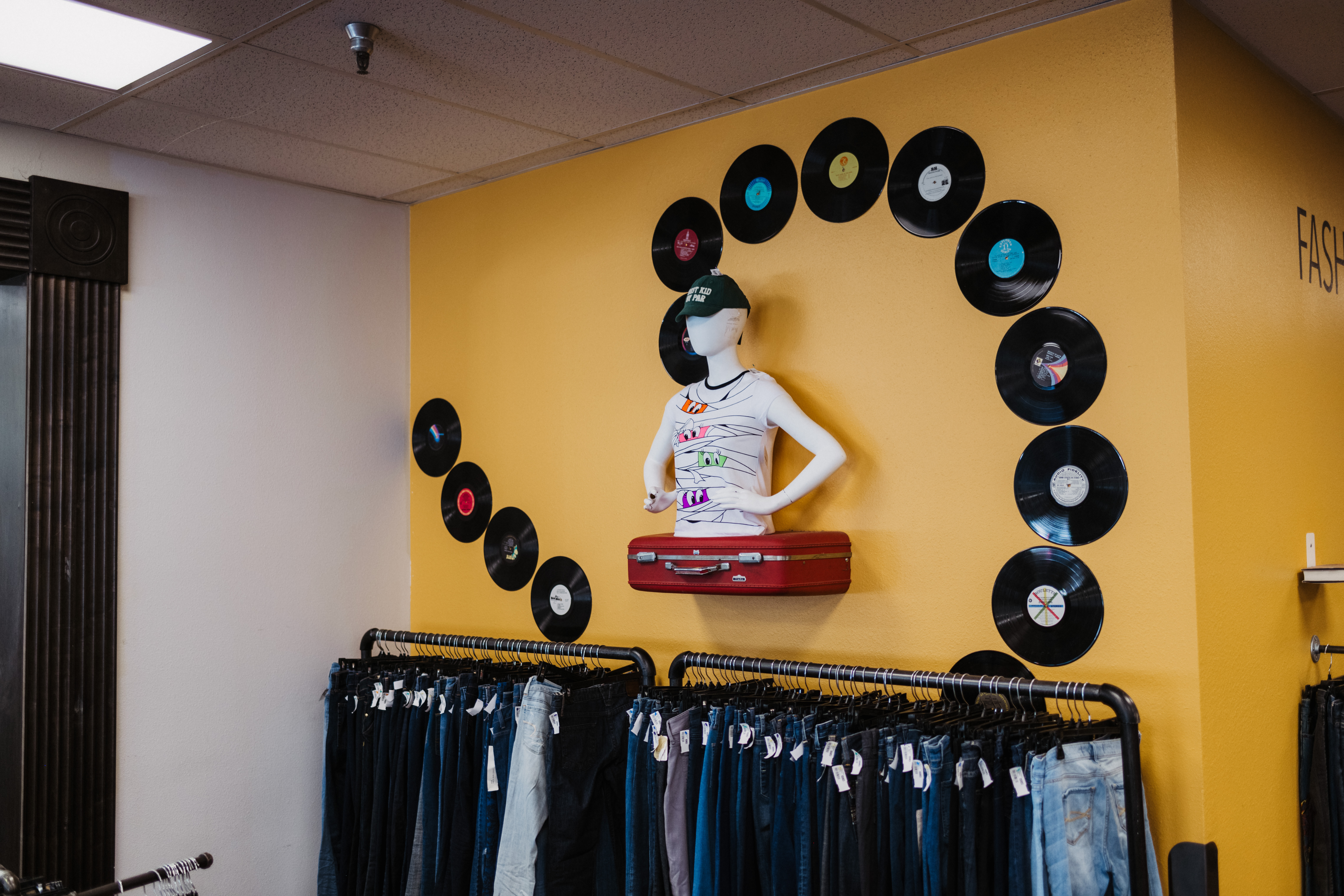 suitcase with mannequins on top and vinyl records decorating the walls