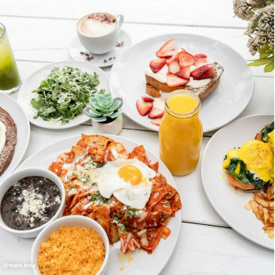 Healthy food table with drinks like orange and eggs and bread