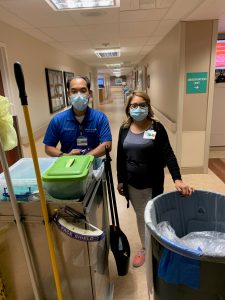 Male and female workers with cleaning equipment at a hospital corridor