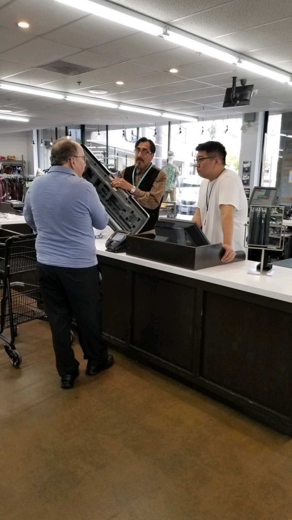 Customer talking to a shop assistant at check out counter at OC Goodwill store Orange County